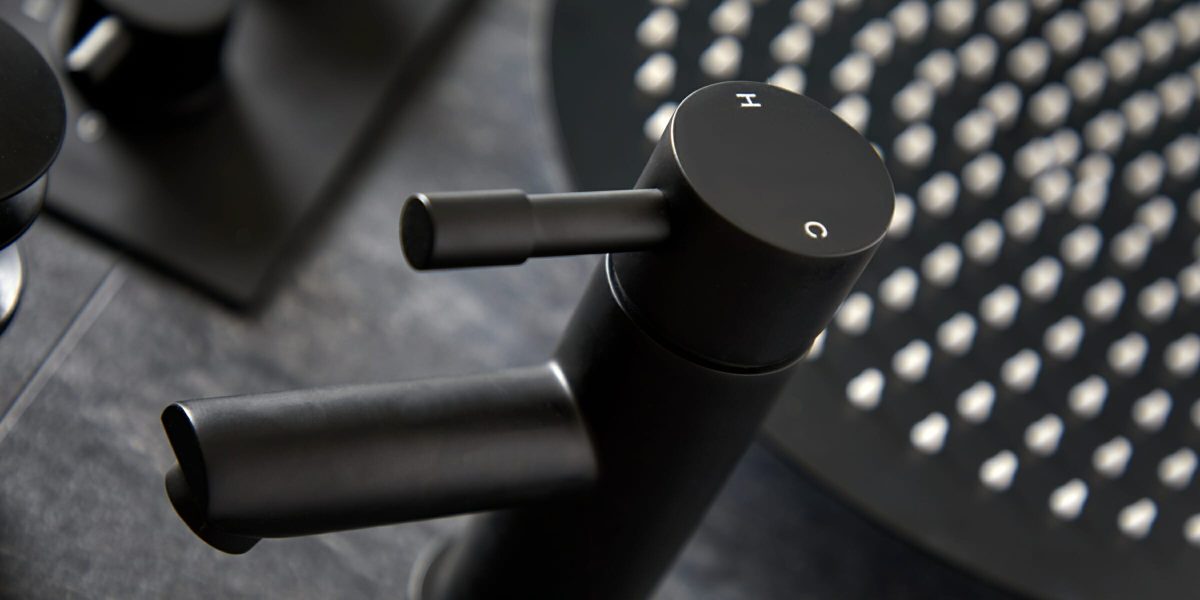 close up of a black basin tap in front of a black shower head