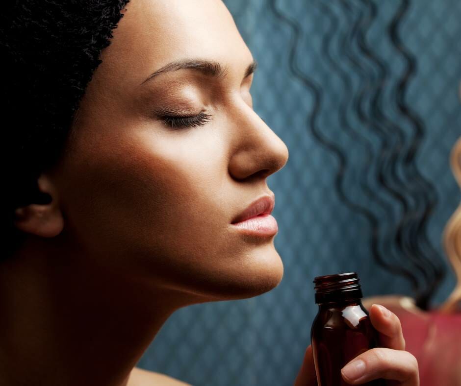 a woman smelling a bottle of essential oils