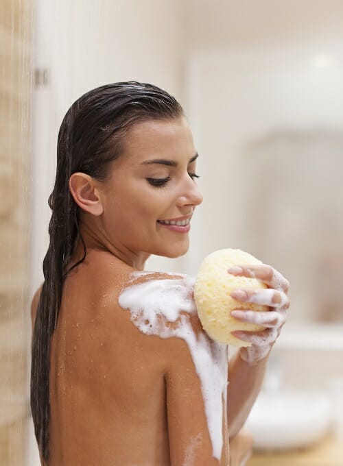 a woman rubbing her shoulder while taking a shower