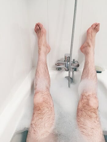 amn in a bath tub with his legs in the air