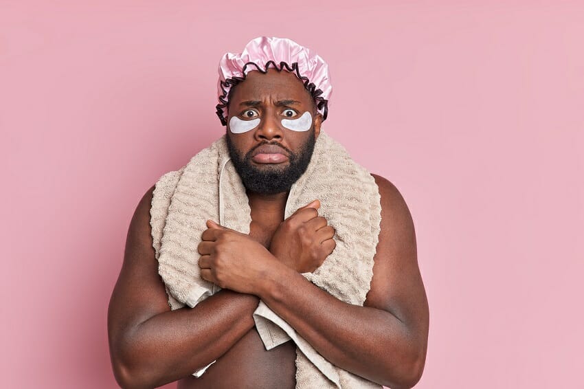 Man in pink shower cap with towel wrapped around shoulders