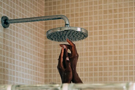 Female hands visible in shower enclosure directly beneath shower flow