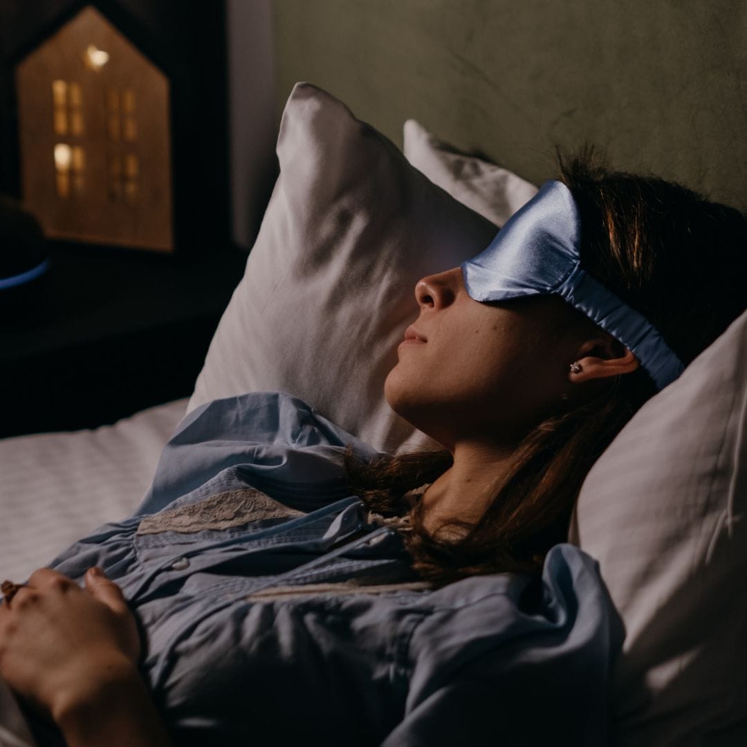 Woman asleep in bed with sleep mask over eyes 
