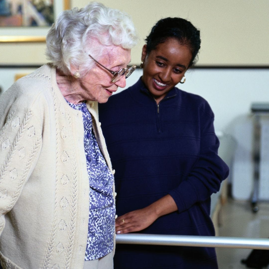 Elderly woman being helped by black carer