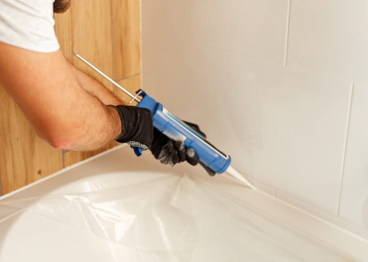 a person applying sealant to a bathtub