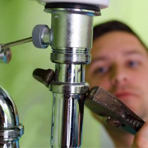 man removing basin tap-with wrench