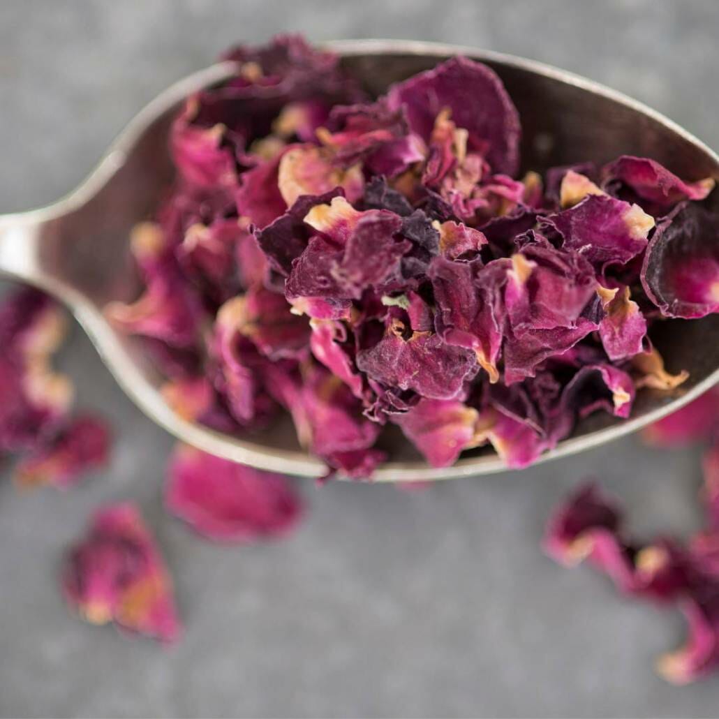 spoon filled with scented pink rose petals